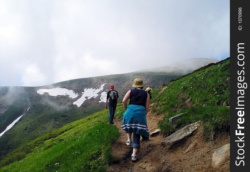 People going up to the peak covered by clouds. People going up to the peak covered by clouds