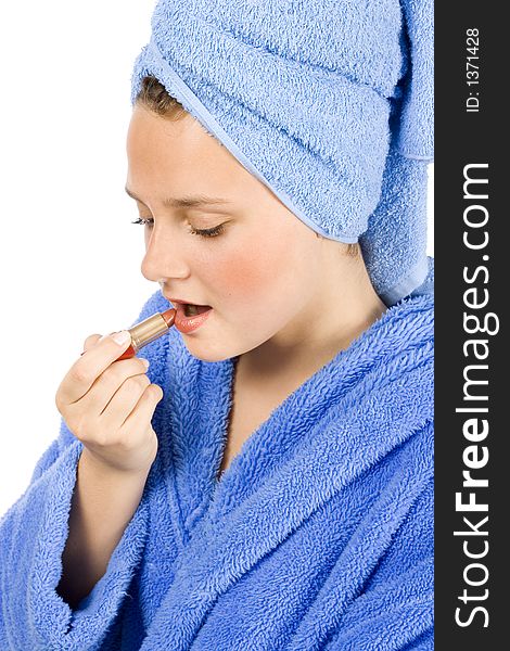 Isolated on white young woman dressed blue bathrobe putting lipstick