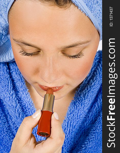 Face of young woman dressed blue bathrobe putting lipstick