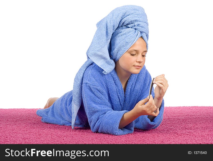 Young woman dressed blue bathrobe and towel filing nails on the pink carpet