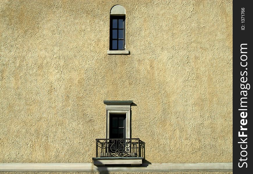 A balcony and a small window on a beige wall. A balcony and a small window on a beige wall.