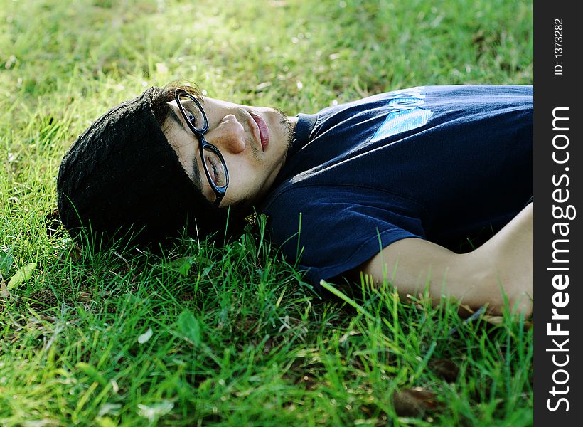 A person with glasses laying in the grass. A person with glasses laying in the grass