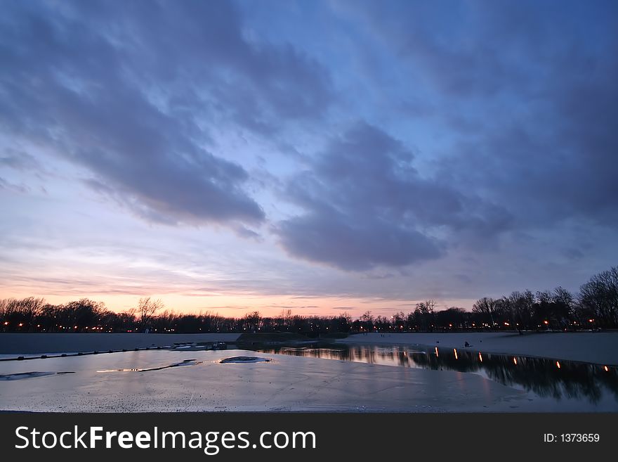 Lake under ice with magnificent cloudy sky at sunset