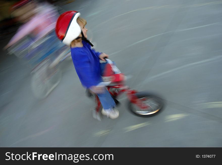 Motion shot of little girl biking with red helmet