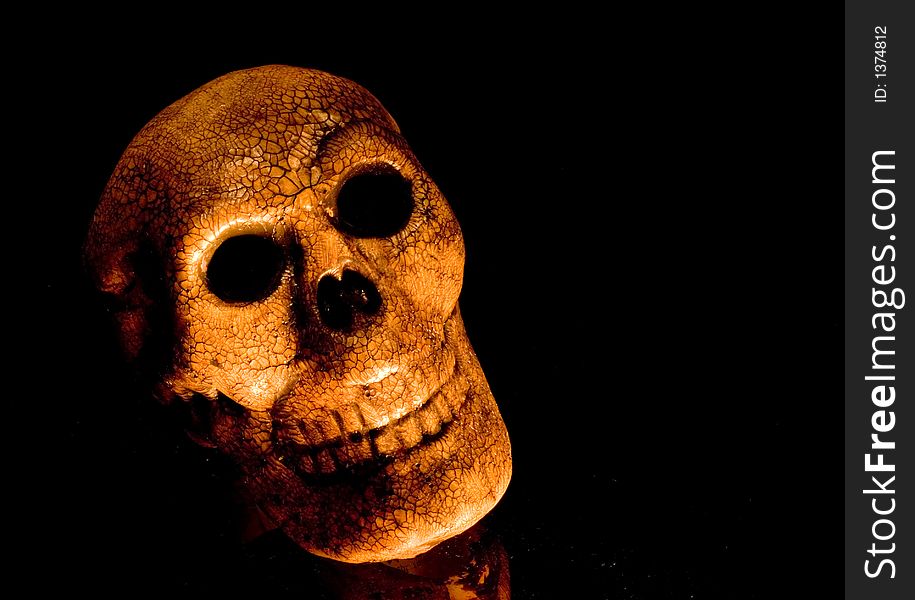 Human skull on black lit up with orange light. Human skull on black lit up with orange light