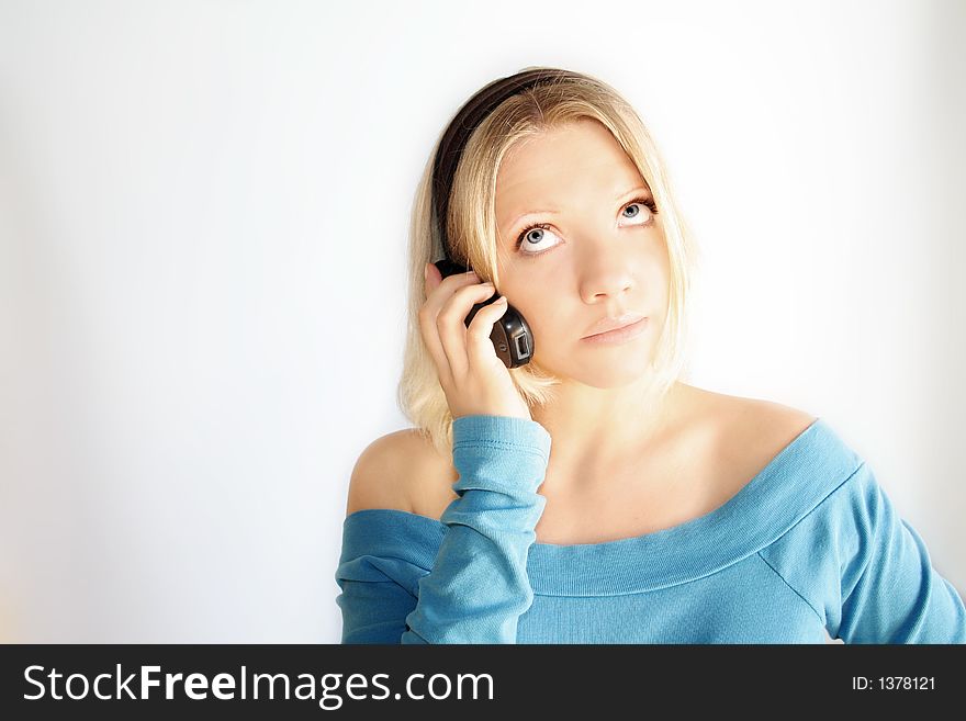 A young blond woman with a mobile phone in her hand. A young blond woman with a mobile phone in her hand