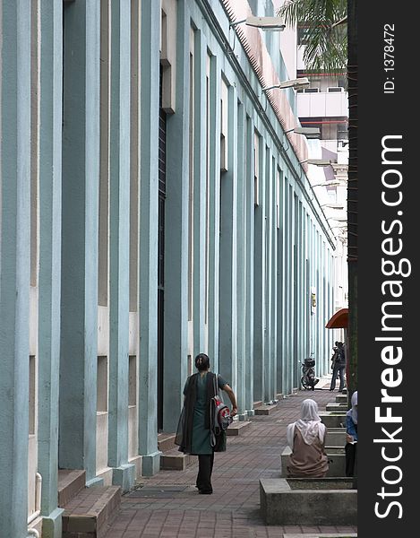 People along a blue building facade with vertical pillars. People along a blue building facade with vertical pillars
