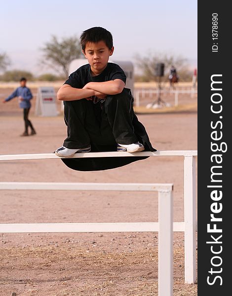 Boy kneeling on rail with arms crossed. Boy kneeling on rail with arms crossed