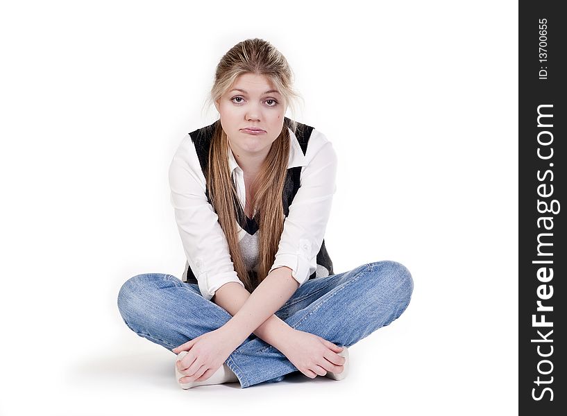 Isolated Pretty Blond Young Woman In Blue Jeans Sitting With Her Legs Crossed