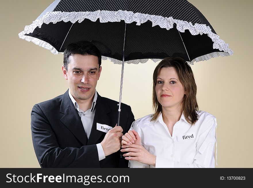 Fired man and woman showing identical situation and staying under the same umbrella