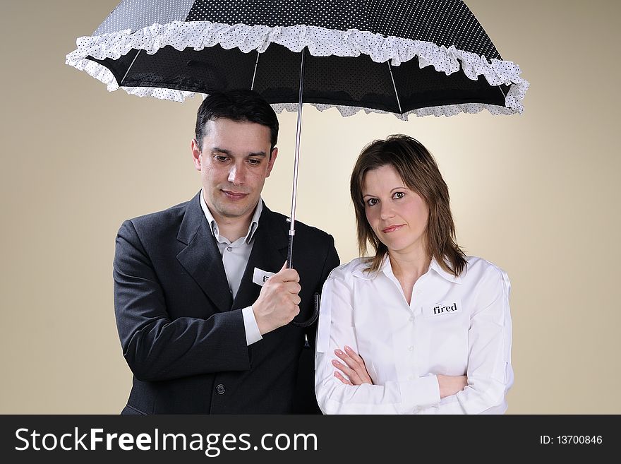 Fired man and woman showing identical situation and staying under the same umbrella