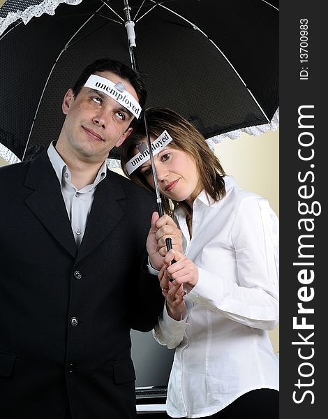 Unemployed man and woman showing identical situation and staying under the same umbrella. Unemployed man and woman showing identical situation and staying under the same umbrella