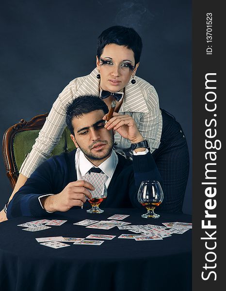 There is cool couple. He smokes cigar and hold glass with cognac. There is cool couple. He smokes cigar and hold glass with cognac.