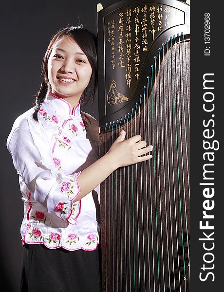 Chinese zither performer in traditional dress with her zither on dark background.
Chinese character on zither is Chinese Tang poetry,also a famous Tang Dynasty poet's calligraphy. It praised the unique charm of the zither. Chinese zither performer in traditional dress with her zither on dark background.
Chinese character on zither is Chinese Tang poetry,also a famous Tang Dynasty poet's calligraphy. It praised the unique charm of the zither