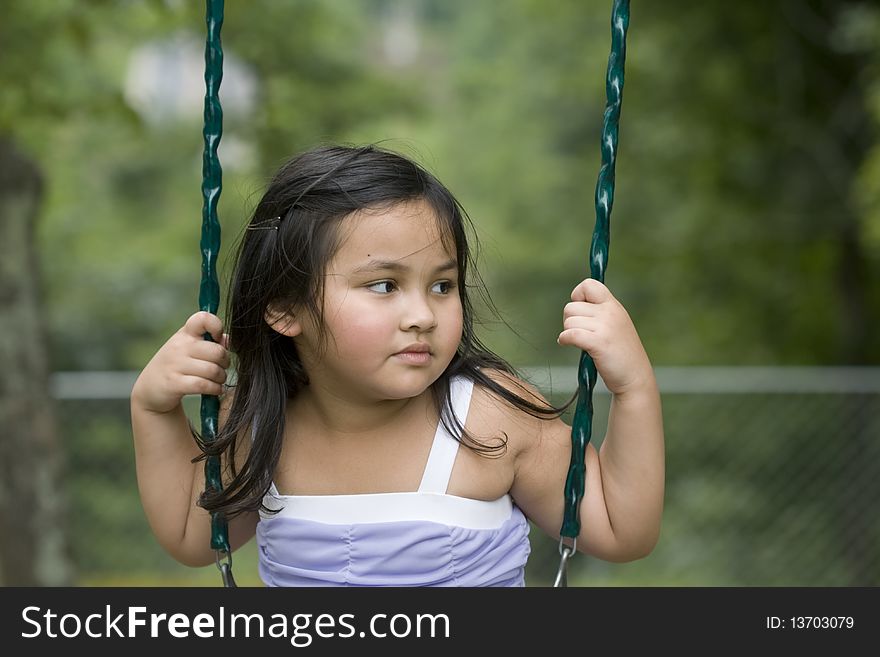 Cute little asian girl with long hair playing on a swing. Cute little asian girl with long hair playing on a swing