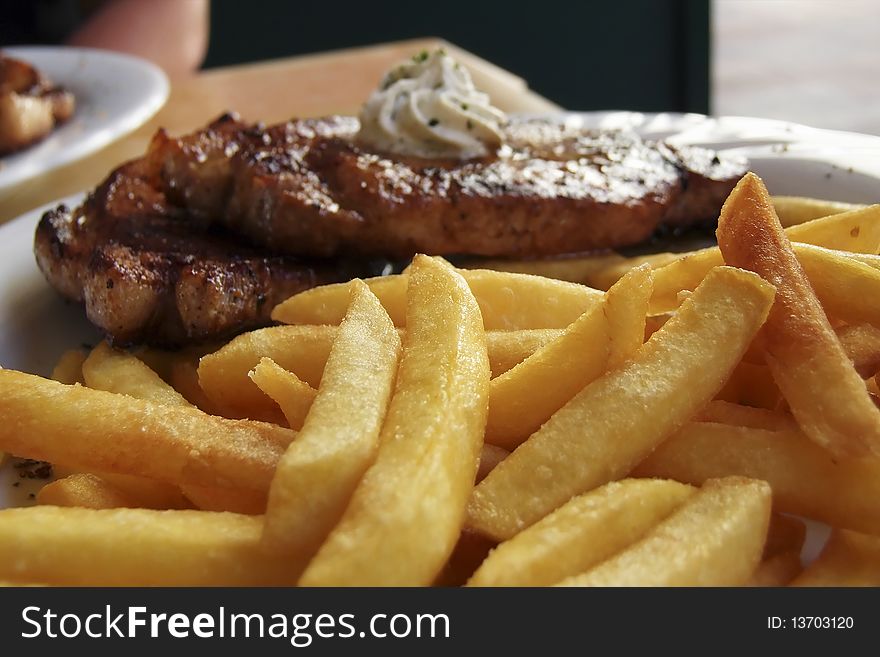 Grilled pork chop with french fries, garnished with garlic butter