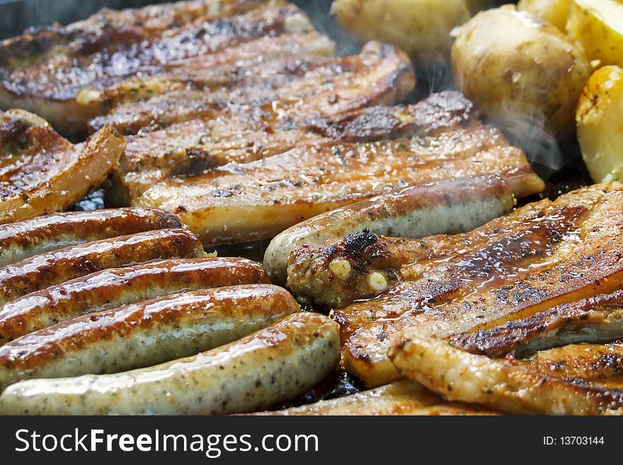 Frying sausages and chopes on a barbecue. potatoes are beside. Frying sausages and chopes on a barbecue. potatoes are beside