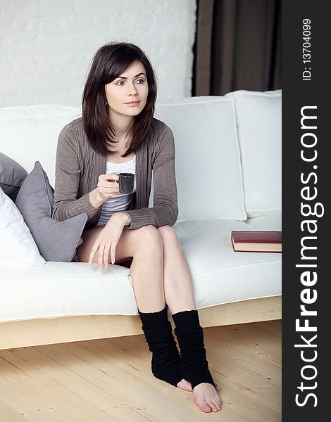 Young beautiful girl in the apartment drinks morning coffee