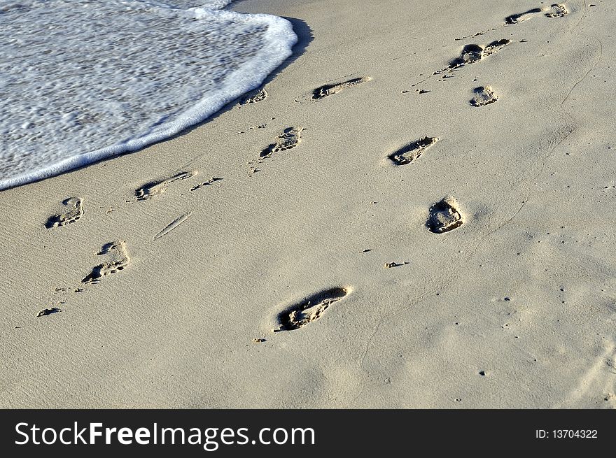 Imprint of human feet in the sand on the beach