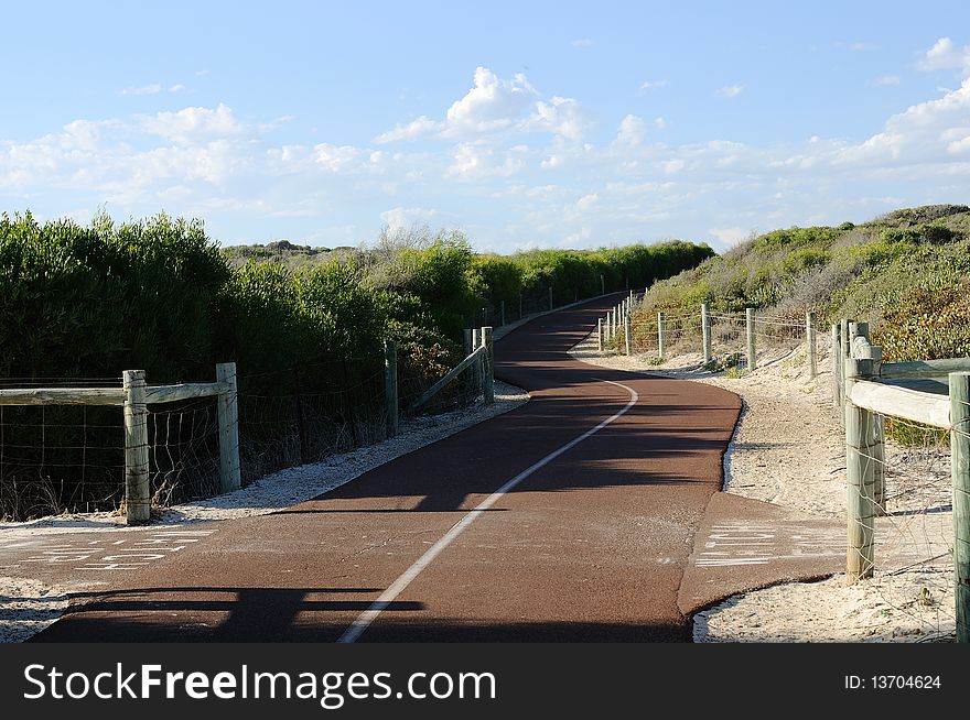 Road passing through the bushes and disappearing into the distance to the hills