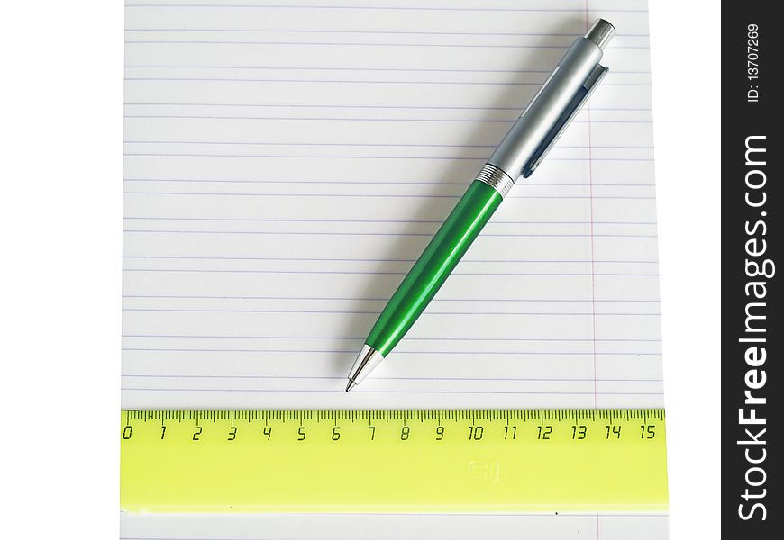 The pen and ruler lays on a school writing-book close up isolated. The pen and ruler lays on a school writing-book close up isolated