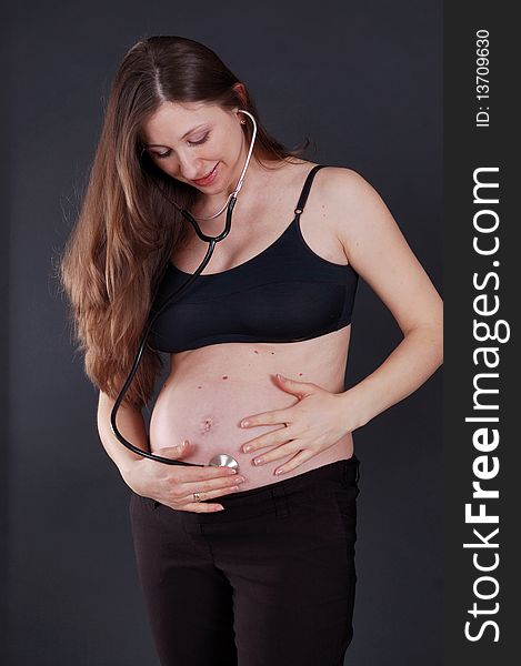 Beautiful pregnant woman, stethoscope examination of the stomach.