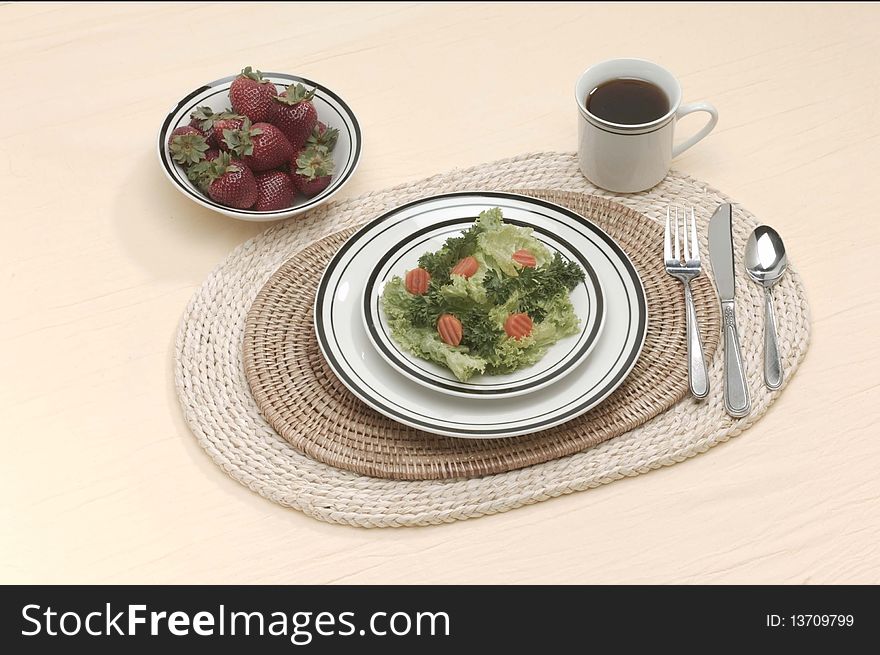 Place setting of salad, coffee and strawberries on a table for a healthy meal