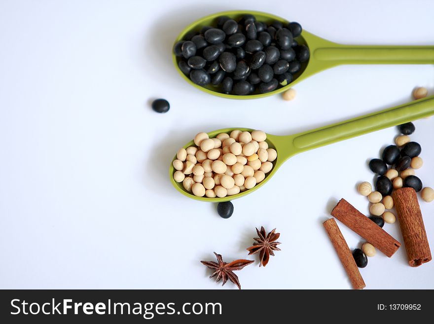 black and yellow beans collect in measuring spoons on white background. black and yellow beans collect in measuring spoons on white background