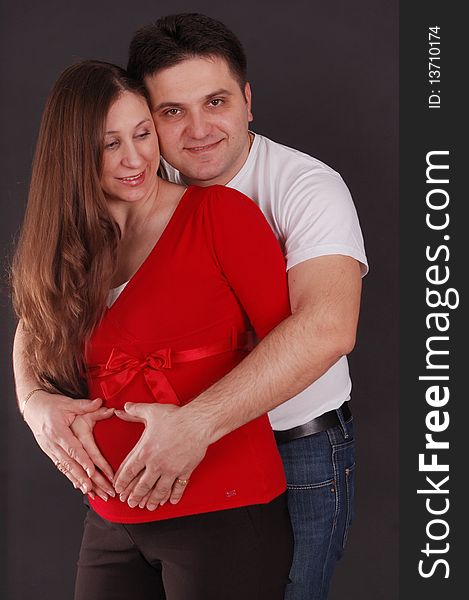 The pregnant woman and the man on a black background