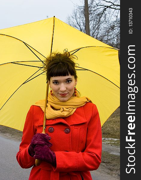 Beautiful girl on red coat with yellow umbrella. Beautiful girl on red coat with yellow umbrella