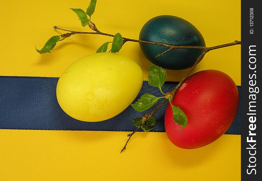 Colored Easter eggs and blue ribbon isolated on yellow