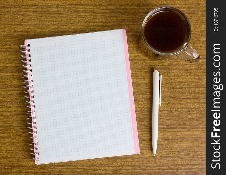 Notebook and a cup coffee on a wooden table