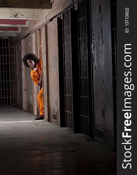 A young man wearing an orange prison jumpsuit makes a face as he peeks out from within his prison cell. Vertical shot. A young man wearing an orange prison jumpsuit makes a face as he peeks out from within his prison cell. Vertical shot.