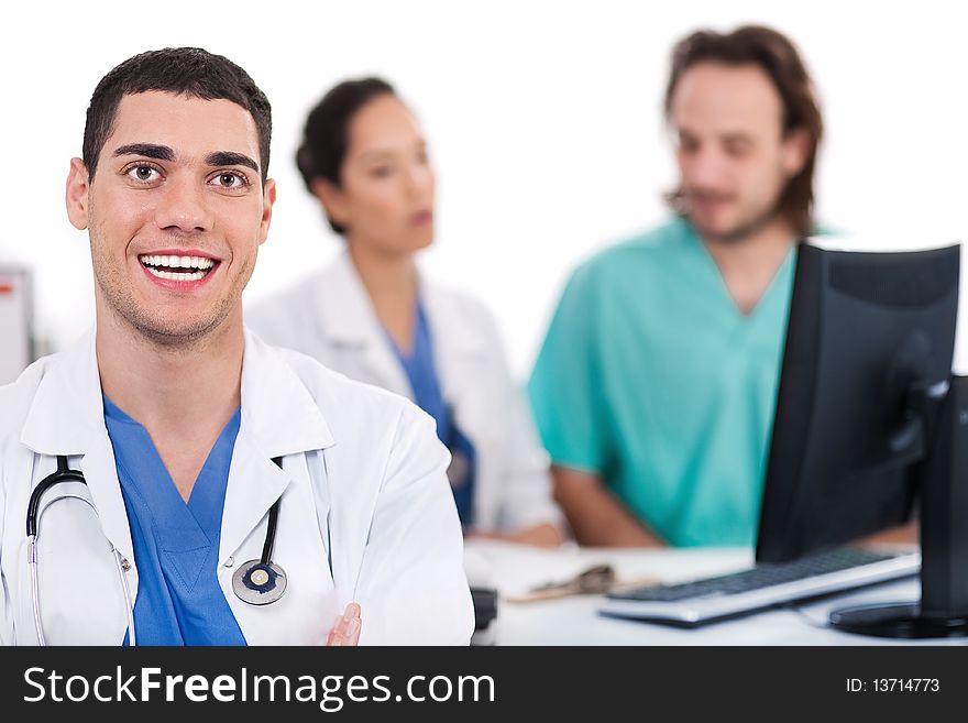 Happy young doctor in focus, two others in out of focus in white background