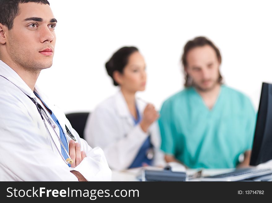 Young doctor thinking deeply, collegues discussing behind with computer in hospital