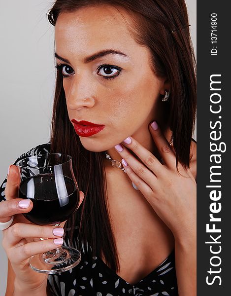 A young beautiful woman with a glass of wine in her hand and in a
white black dress and red lips for light gray background. A young beautiful woman with a glass of wine in her hand and in a
white black dress and red lips for light gray background.