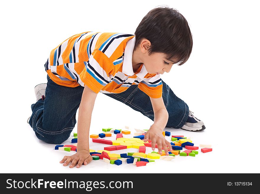 Cute kid in process of joining the blocks over white background