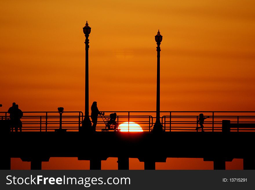 Huntington Beach Pier in California. Sunset shot with a little girl running ahead of her Mom excitedly.