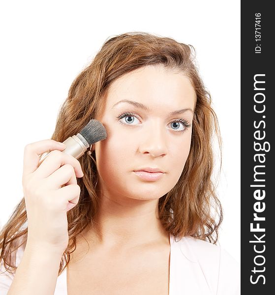 Young woman putting make up on her face. Isolated over white