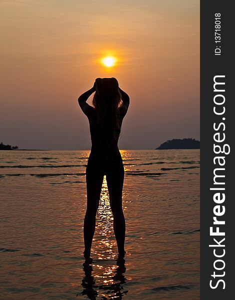 Young long hair woman on coastline at sunset time