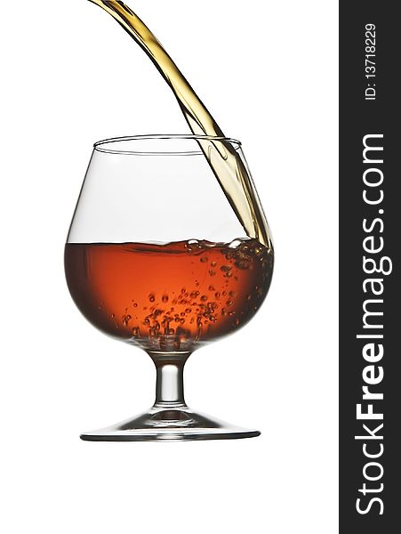 Pouring cognac brandy in glass isolated on white