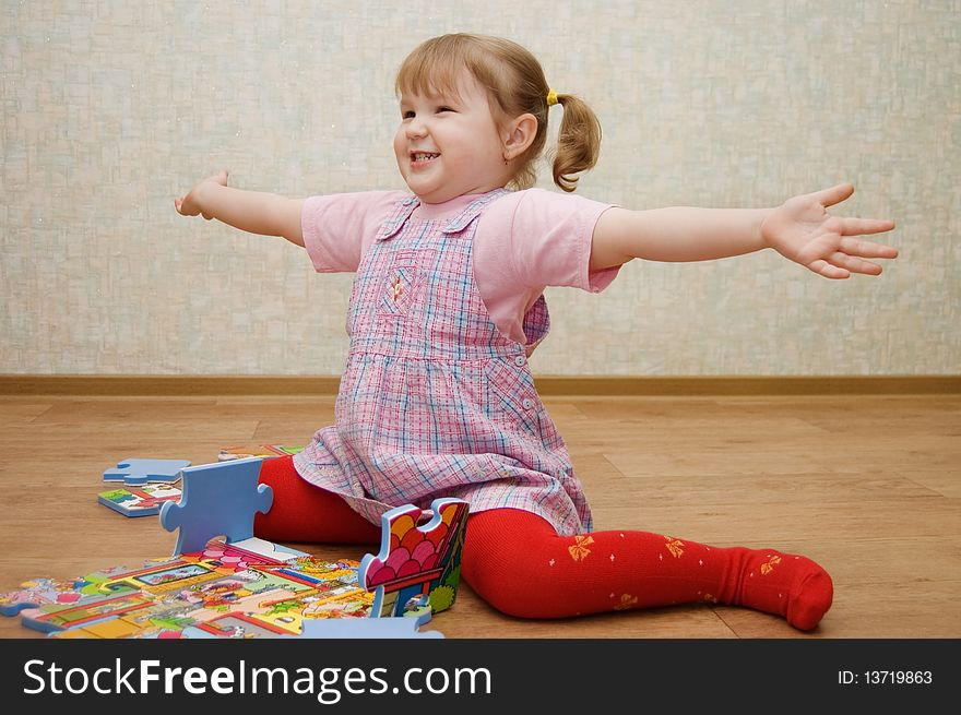 Little girl collects puzzles in a room