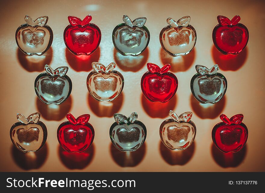 3 rows of colorful plastic transparent apples on light background top view. 3 rows of colorful plastic transparent apples on light background top view