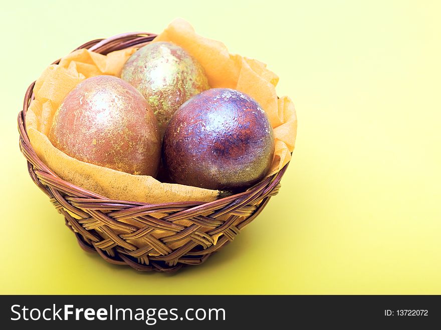 Easter eggs decorated with a foil in a basket on cheerful yellow background. Easter eggs decorated with a foil in a basket on cheerful yellow background
