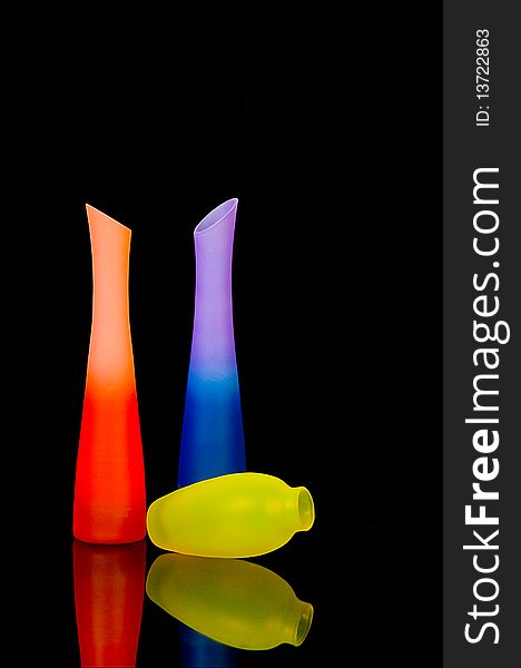 Bright glass vases on black background with reflection