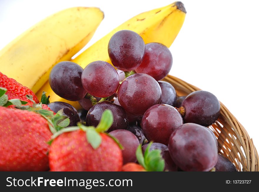 Strawberries, grapes and bananas in a straw basket. Strawberries, grapes and bananas in a straw basket