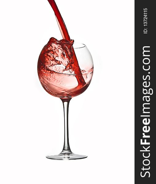 Pouring red wine in large glass isolated white