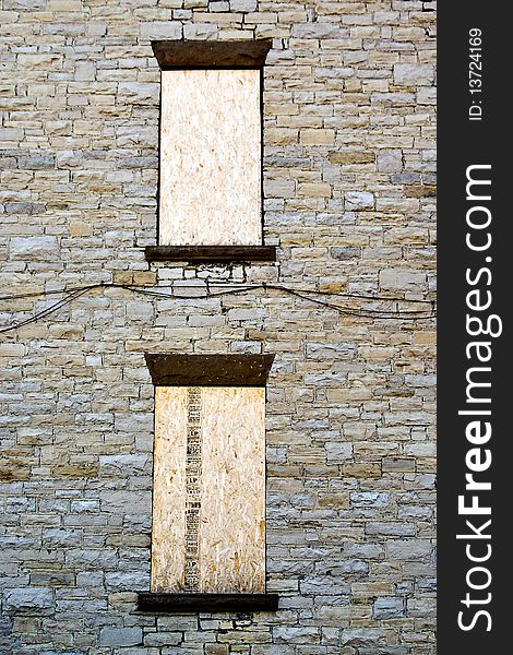 Two boarded-up windows on a stone wall texture. Two boarded-up windows on a stone wall texture.