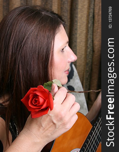 Beautiful brunette female with a guitar, holding a rose. Beautiful brunette female with a guitar, holding a rose