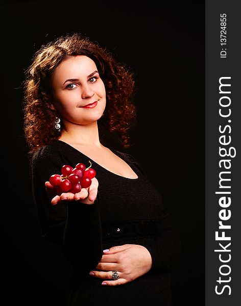 Portrait of a young woman holding grapes on her hand. Studio shot. Portrait of a young woman holding grapes on her hand. Studio shot.